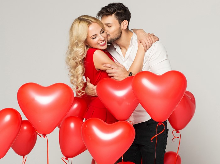 Couple kissing surrounded by heart balloons
