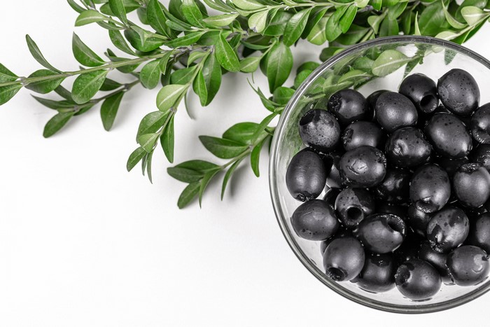 Black olives in a bowl with green branches
