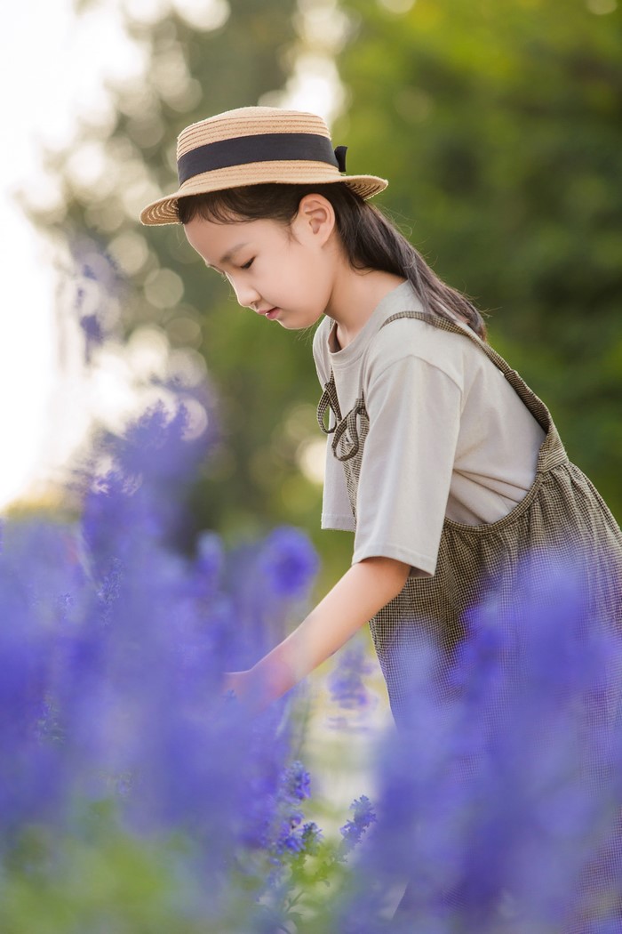 Young Asian Girl in Hat Among Purple Flowers