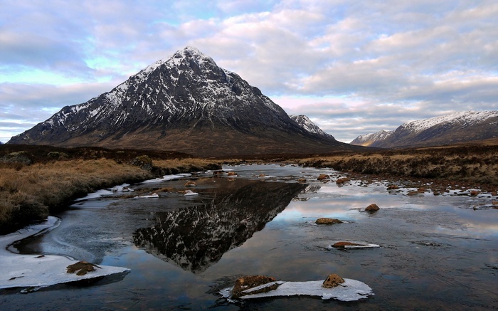 Snow-capped mountain reflected in a partially frozen river