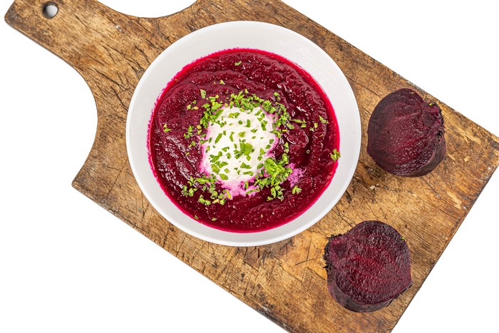Beetroot soup with sour cream on a cutting board