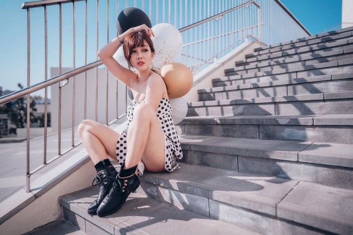Asian woman sitting on stairs with balloons