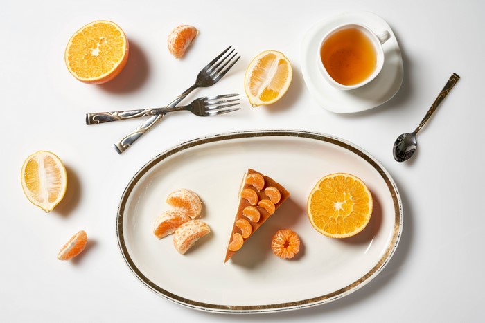 Slice of cake with oranges and tea
