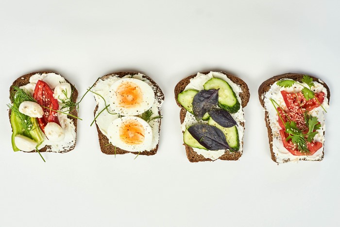 Four open-faced sandwiches with various toppings