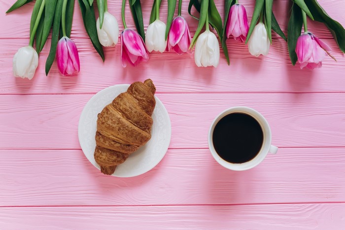 Tulips, Coffee, and Croissant on Pink Wooden Table