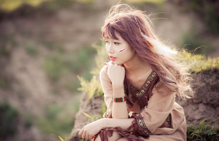 Asian woman with brown hair and face paint sitting outdoors