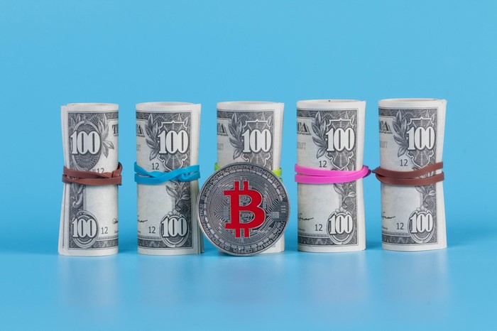 Rolls of US Dollar Bills and Bitcoin Coin