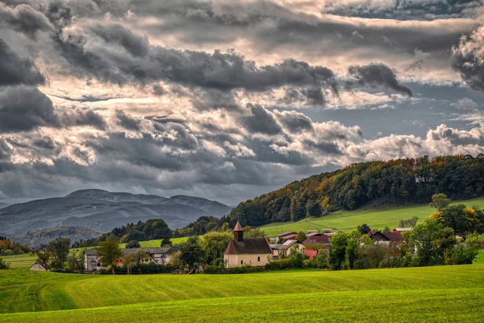 Village with church in Upper Austria with mountains and clouds