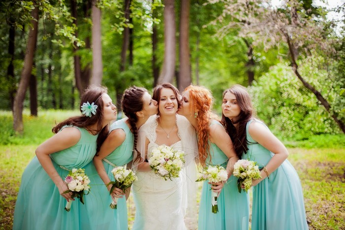 Bride and bridesmaids sharing kisses with bouquets