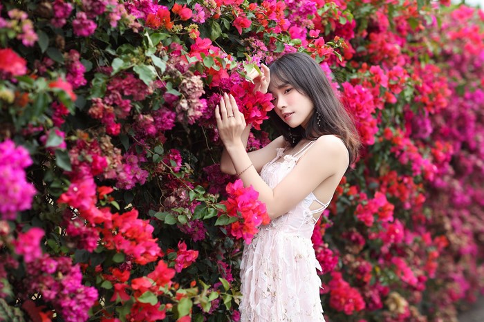 Asian woman in a dress posing near flowers