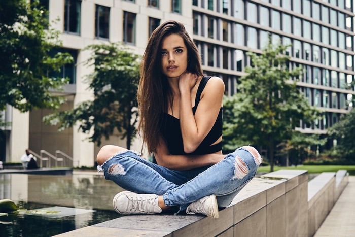 Brunette girl in ripped jeans sitting in lotus position