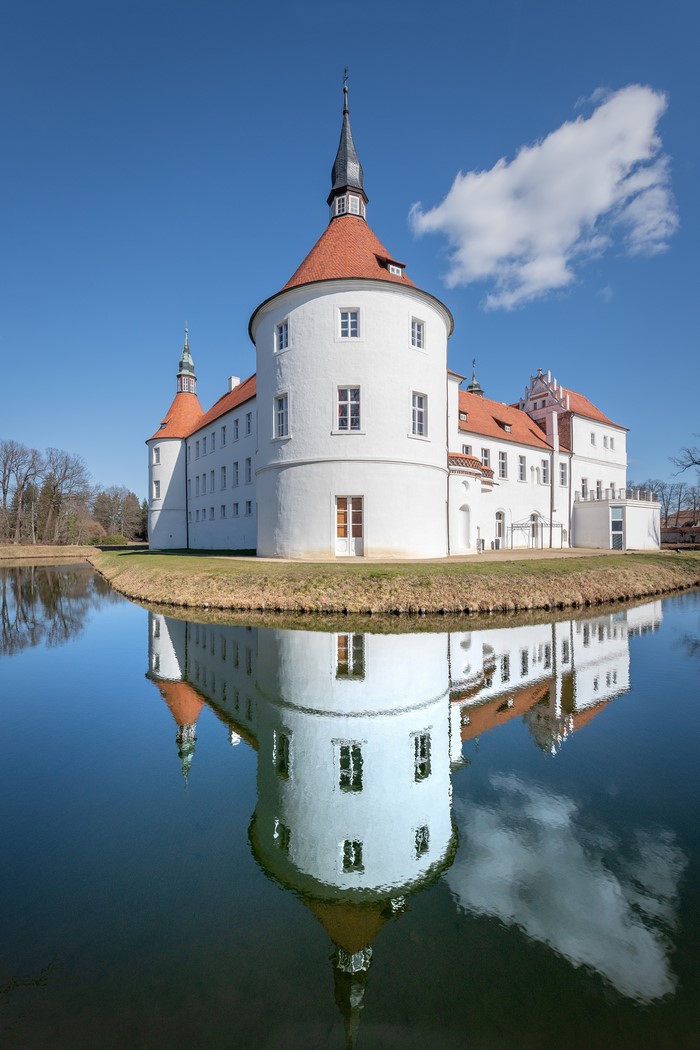Schloss Dennenlohe castle reflected in a pond in Germany