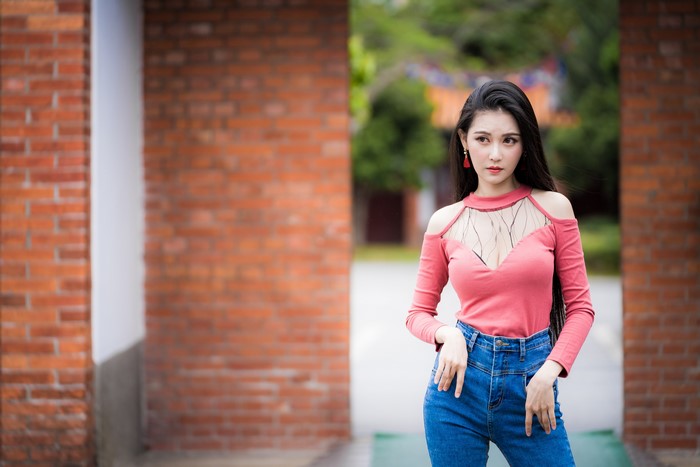 Asian woman in pink top and jeans posing