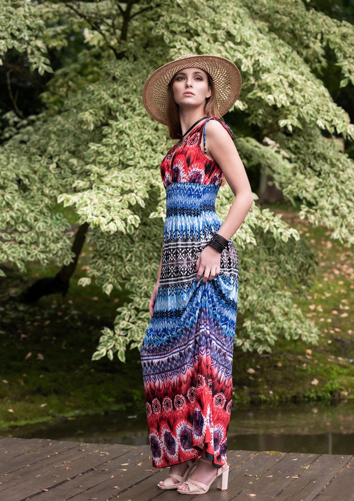 Woman in a patterned dress and hat posing outdoors