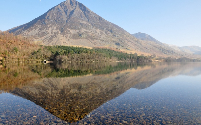 Mountain reflected in a clear lake with a boathouse