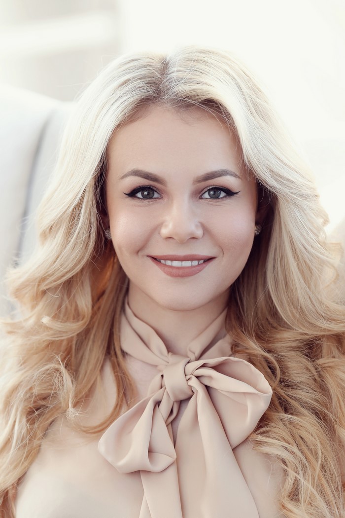 Blonde woman with a bow tie blouse smiling