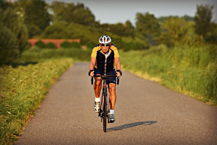 Man Cycling on a Road with Greenery