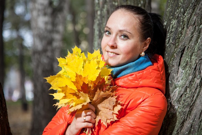 Woman in orange jacket holding autumn leaves
