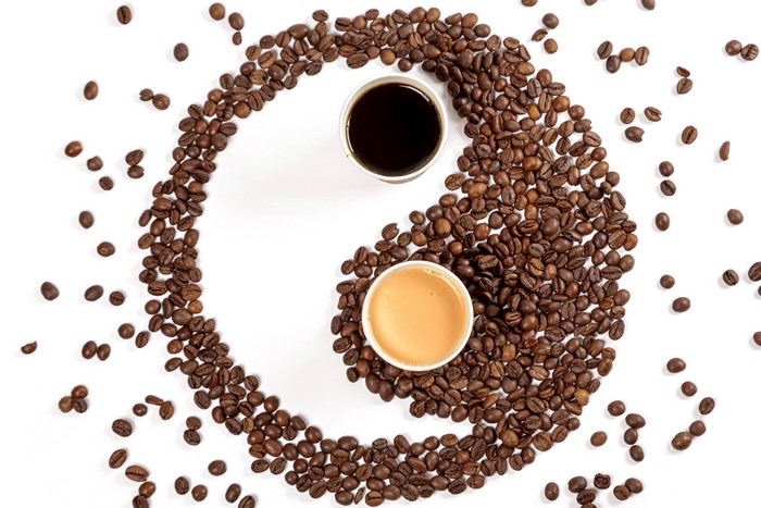 Coffee beans arranged in Yin-Yang symbol with two cups of coffee