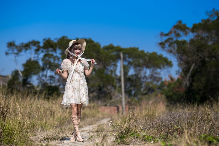 Asian woman in dress and hat posing outdoors