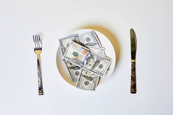 Money on a plate with fork and knife