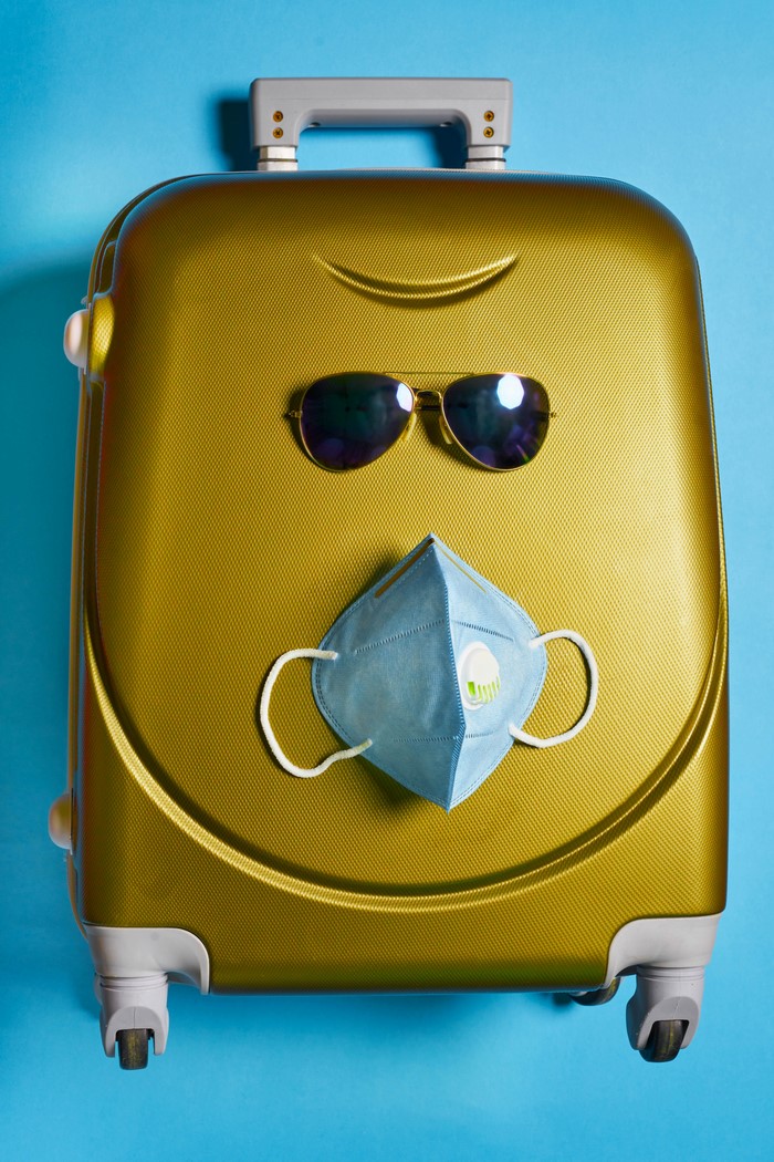 Suitcase with sunglasses and face mask