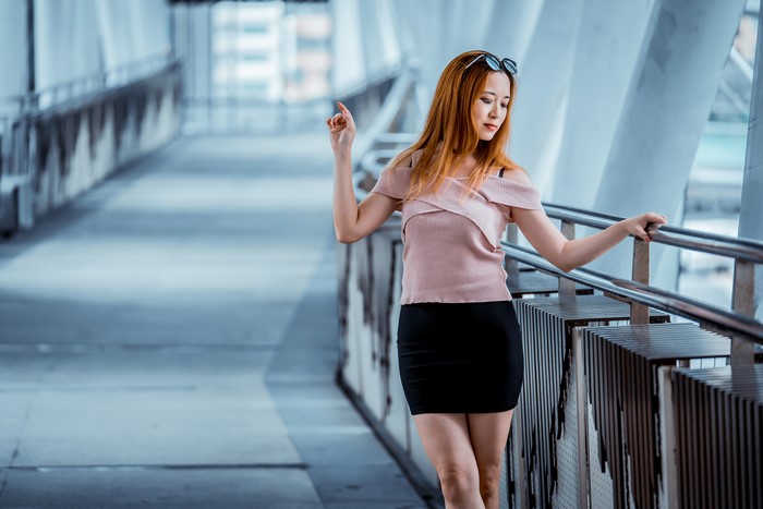 Woman in pink blouse and black skirt on a walkway