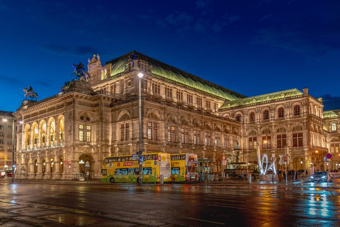 Vienna State Opera at night with double-decker buses