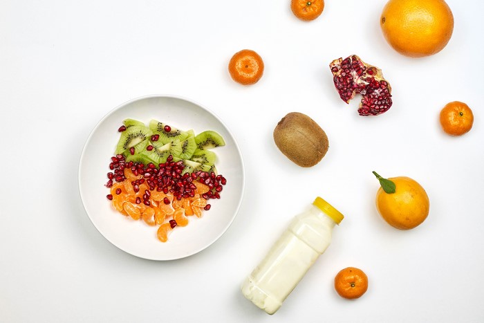 Fruit salad with kiwi, mandarin, pomegranate, and a bottle of milk