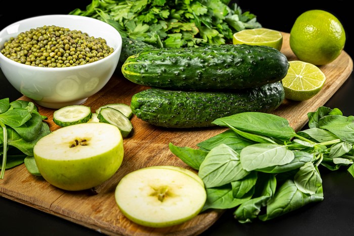 4K Vegetables with Cucumbers, Apples, Green Peas, and Lime on Cutting Board