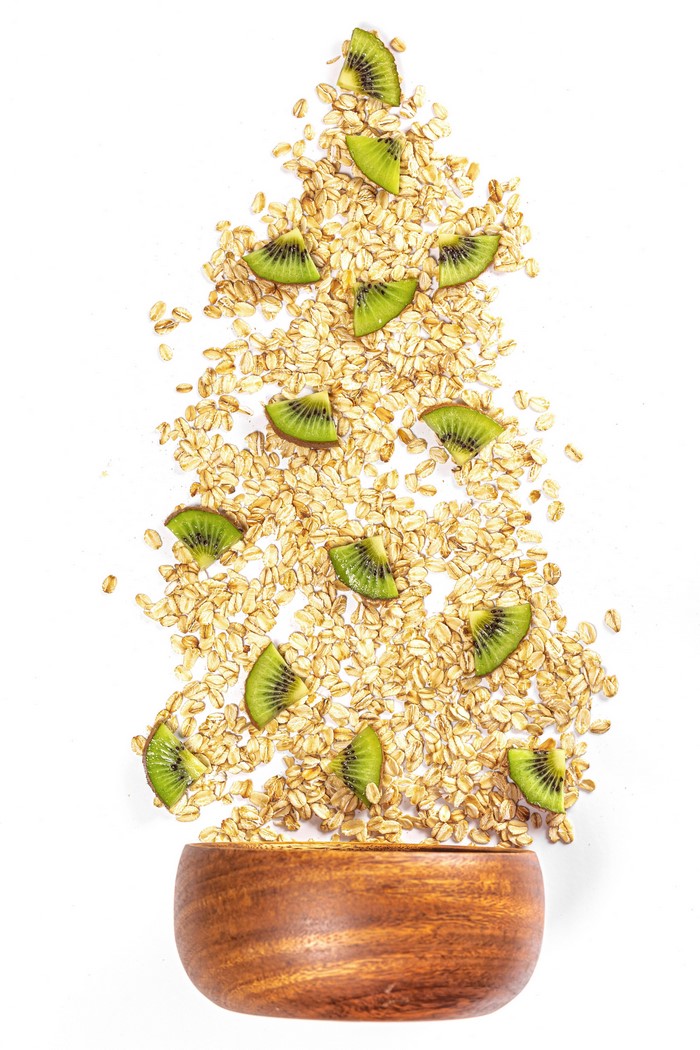 Oatmeal and kiwi slices scattered on a white background