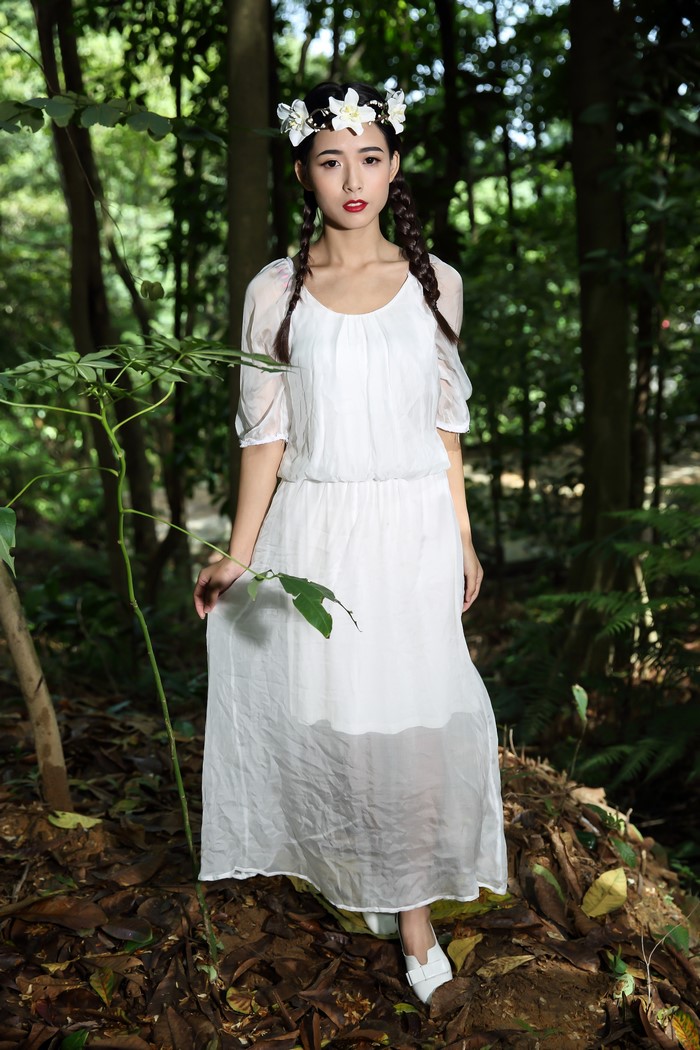 Asian girl with braids and flower wreath in a forest