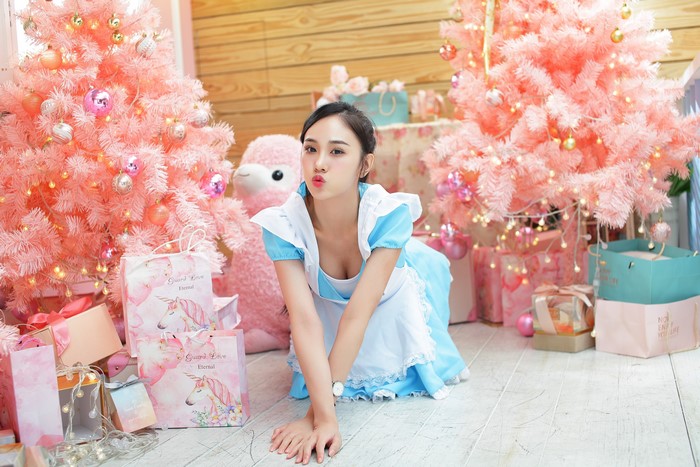 Woman in Alice costume with pink Christmas trees and gifts