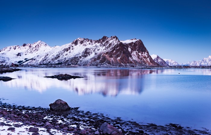 Snowy Lofoten Mountains reflected in calm water, Norway