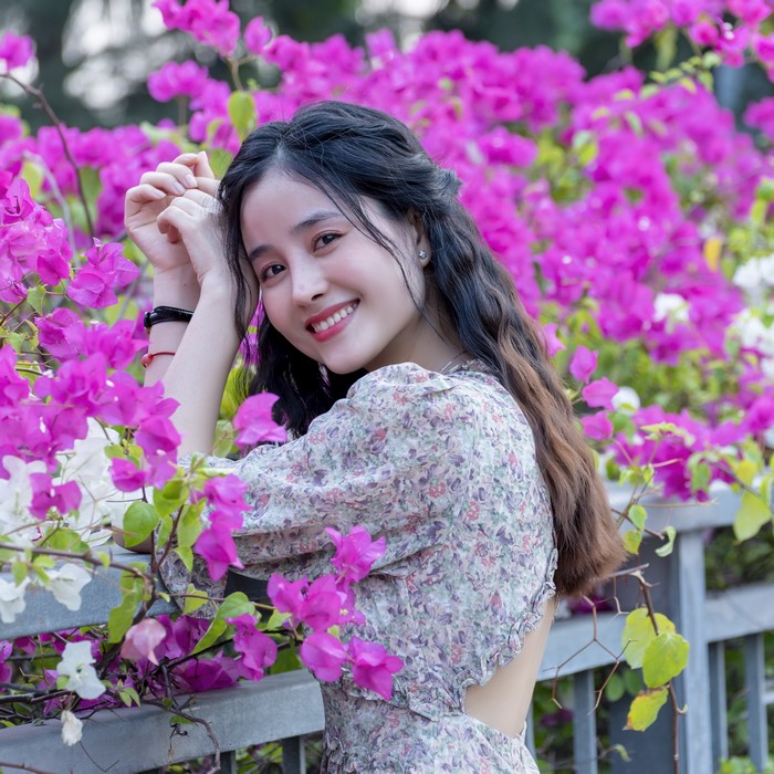 Asian woman smiling among pink flowers