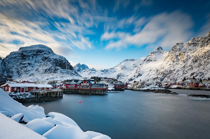 Rorbu houses in Lofoten, Norway, with snowy mountains and clouds