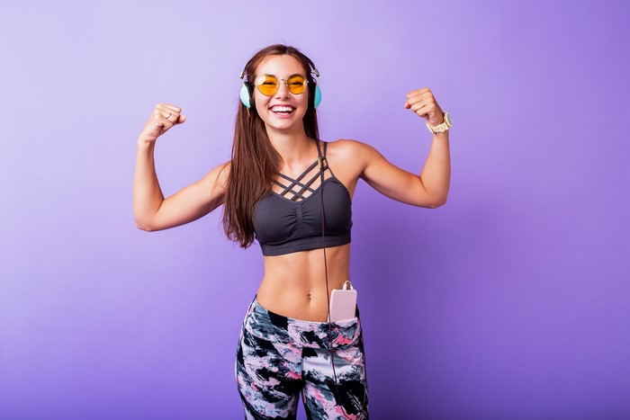 Woman in headphones and glasses flexing muscles