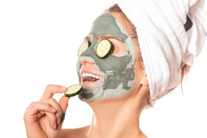 Woman with mud mask and cucumber slices