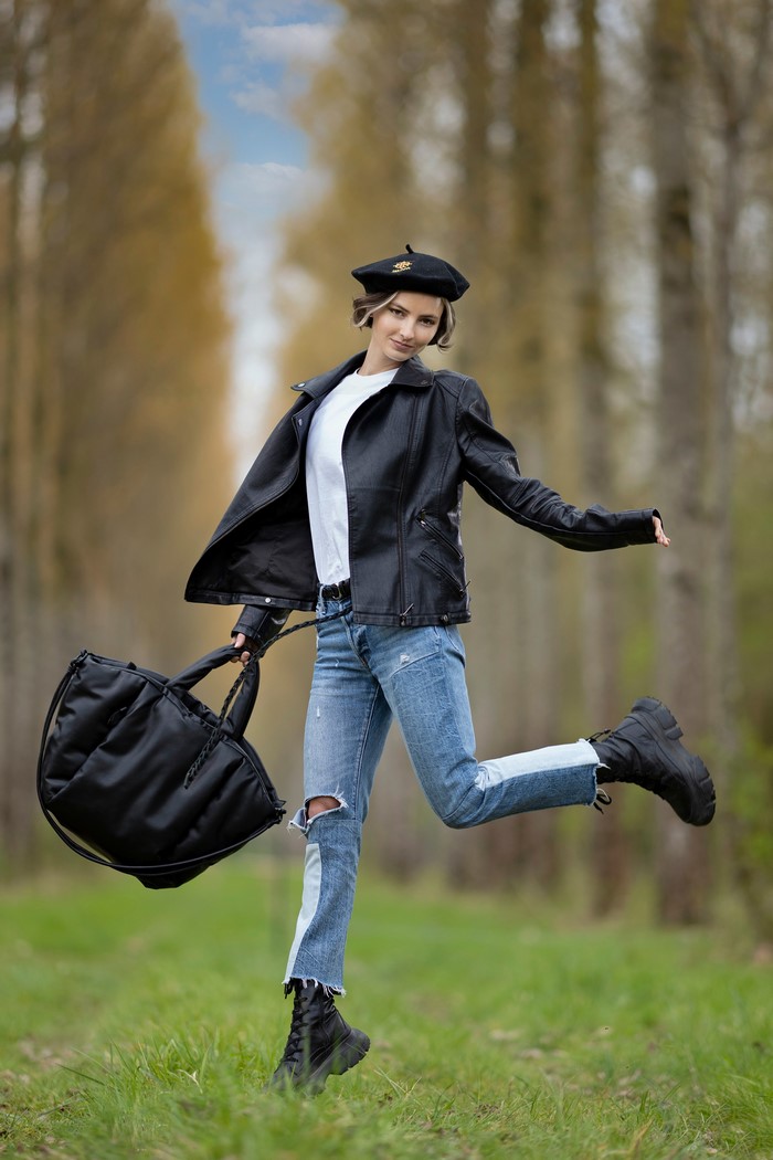 Alena in a leather jacket and beret holding a handbag