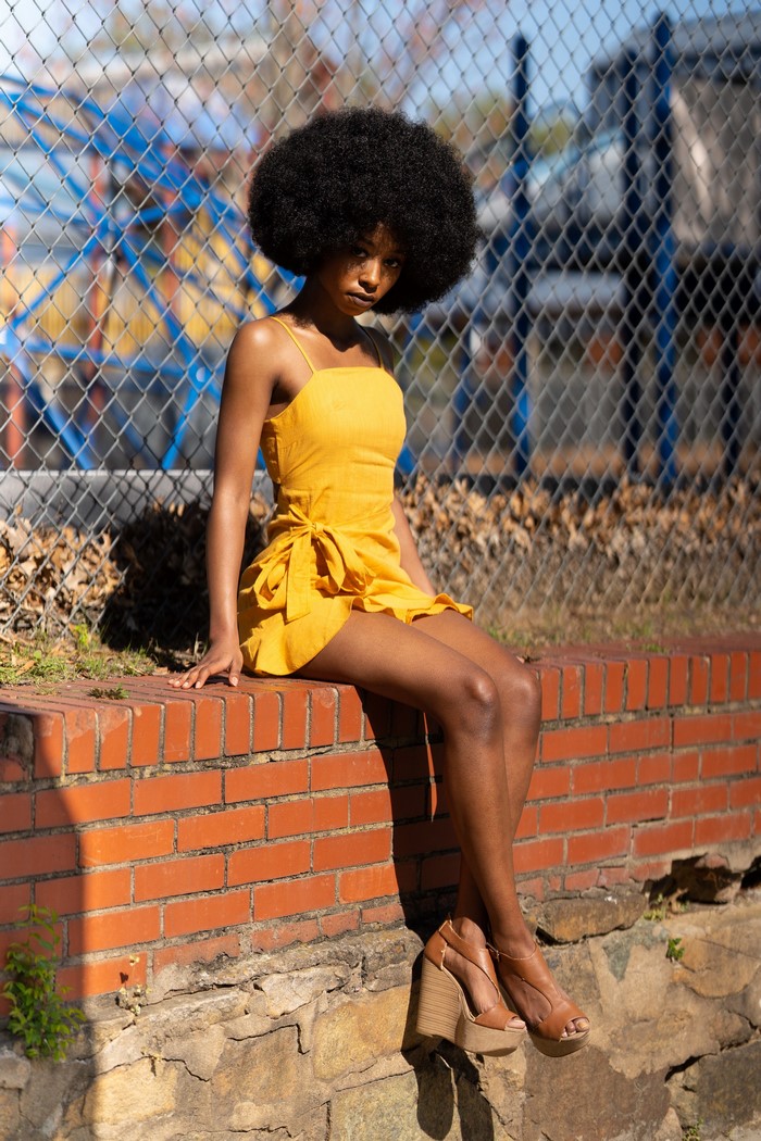 Woman with afro sitting on brick wall
