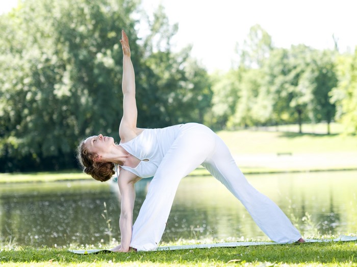 Woman in white doing yoga in a park