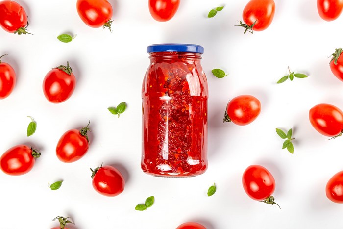 Tomatoes and Jar of Ketchup on White Background