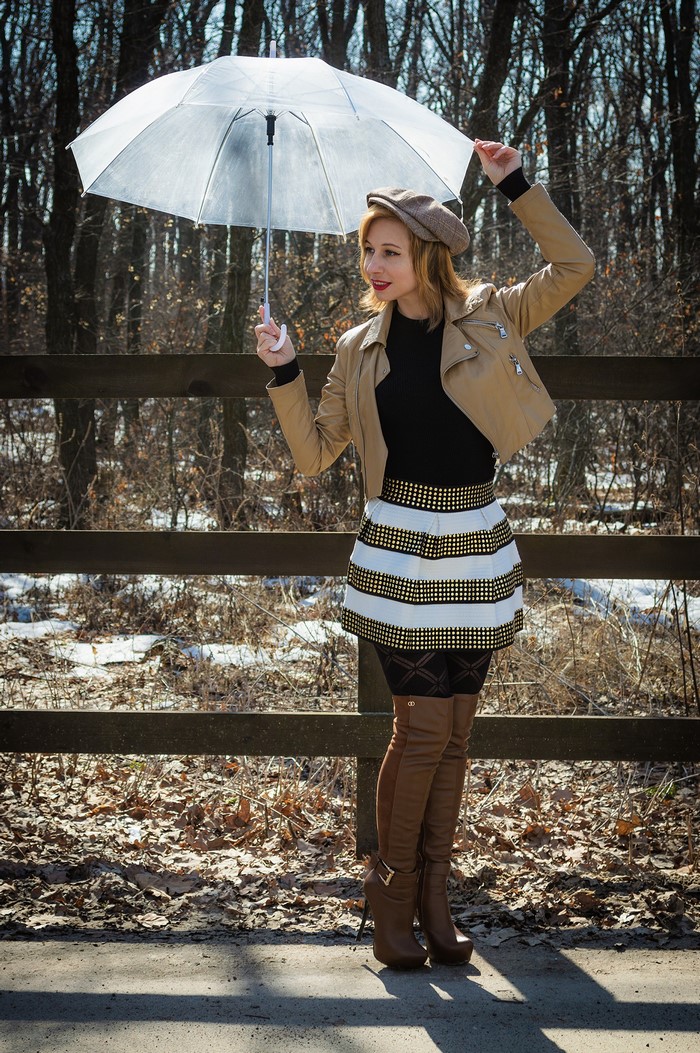 Woman in jacket and skirt holding umbrella