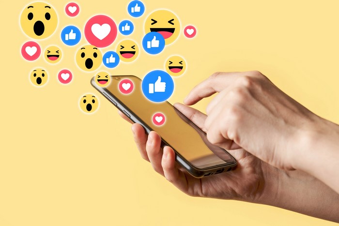 Smartphone with social media reactions on yellow background