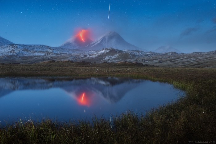 Volcano eruption reflected in lake under starry sky, Kamchatka, Russia