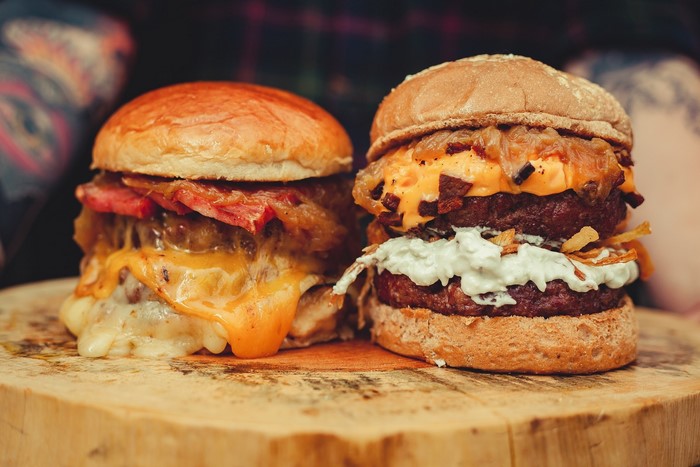 Two gourmet burgers with melted cheese and bacon