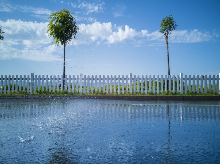 Trees and fence with water splashes on a sunny day