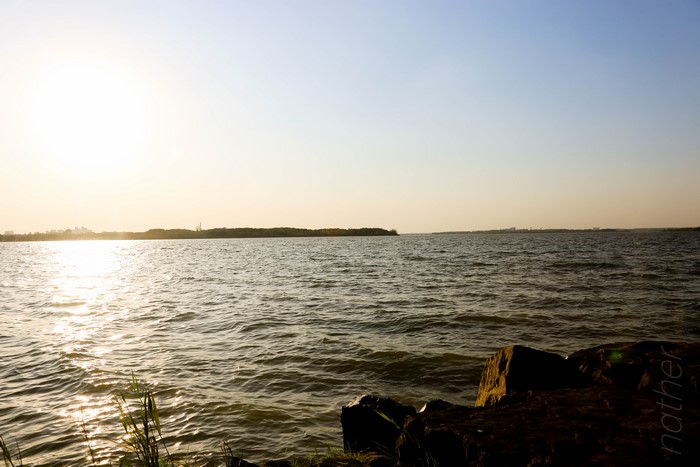4K lake with distant city skyline and rocks