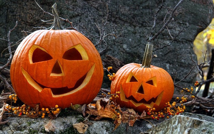 Two carved Halloween pumpkins on a rock