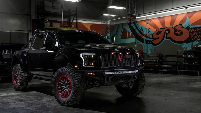 Black Ford F-150 Raptor pickup truck in a garage